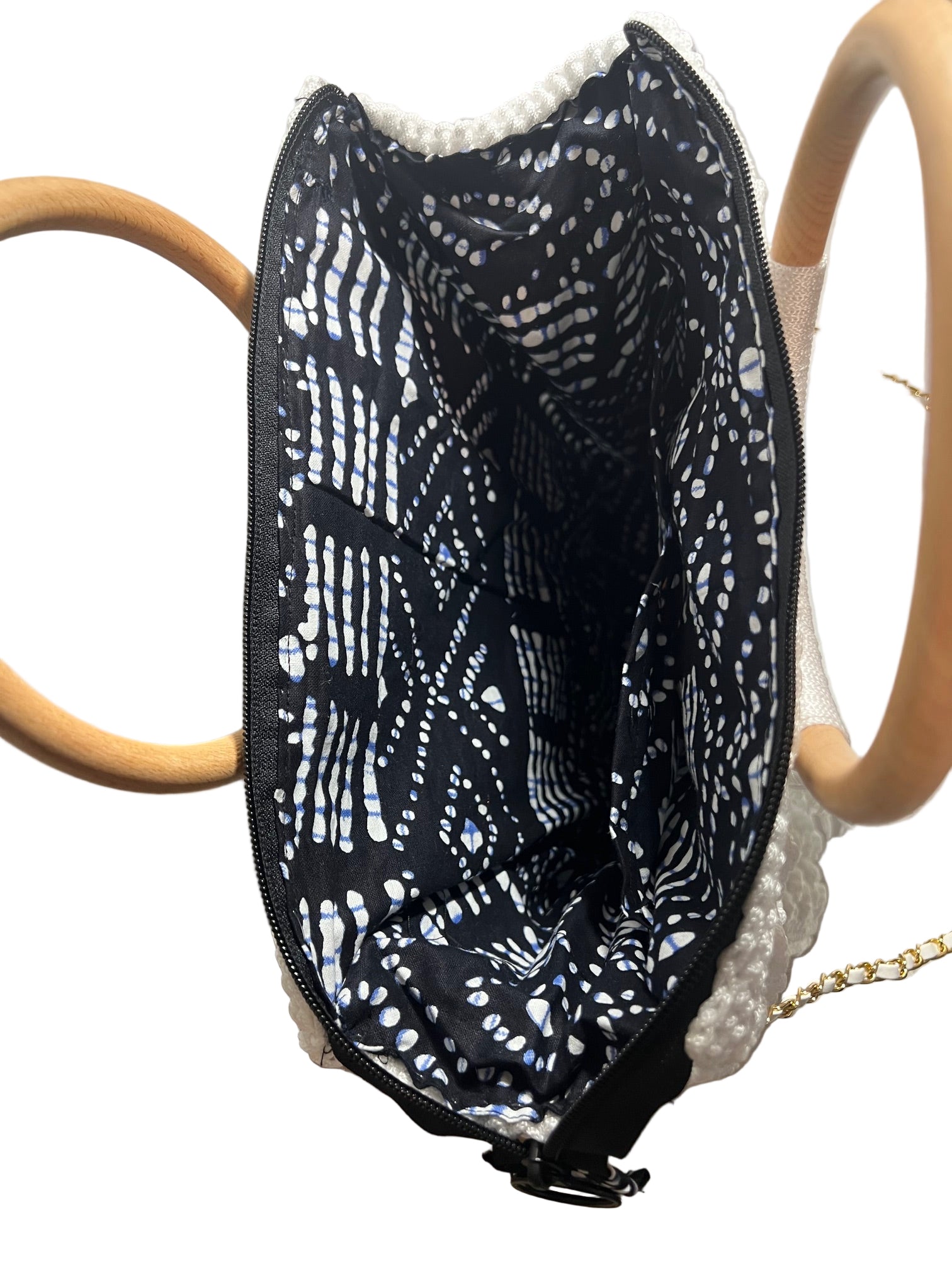Interior view of a handcrafted trapezoid handbag with black patterned lining and wooden handles