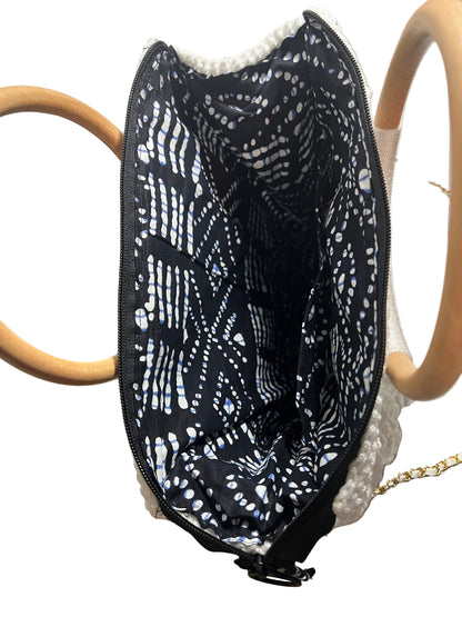 Interior view of a handcrafted trapezoid handbag with black patterned lining and wooden handles