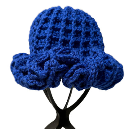 Handmade blue ruffle hat with textured knit design displayed on black stand